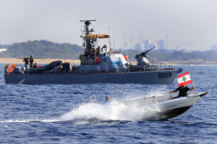 Lebanon Israel Lebanese protesters on a motorboat carry their national flag as they sail in front on an Israeli Navy vessel during a demonstration demanding Lebanon's right to its maritime oil and gas fields, in the southern marine border town of Naqoura, Lebanon, Sunday, Sept. 4, 2022. The protest came days before the mediating U.S. envoy is scheduled to land in Beirut to continue maritime border talks. (AP Photo/Mohammed Zaatari)