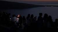 Wisatawan menyaksikan matahari terbenam dari kastil Oia, di pulau Santorini, Yunani, Selasa (30/8/2022) waktu setempat.  
