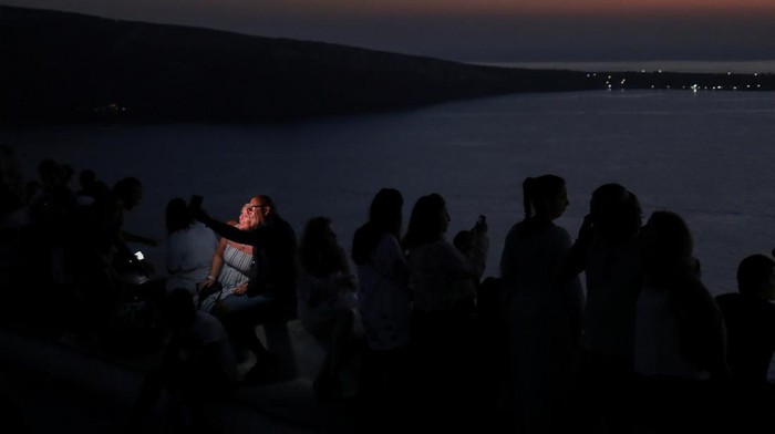 Tourists watch the sunset from the castle of Oia, on the island of Santorini, Greece, August 30, 2022. REUTERS/Louiza Vradi     TPX IMAGES OF THE DAY
