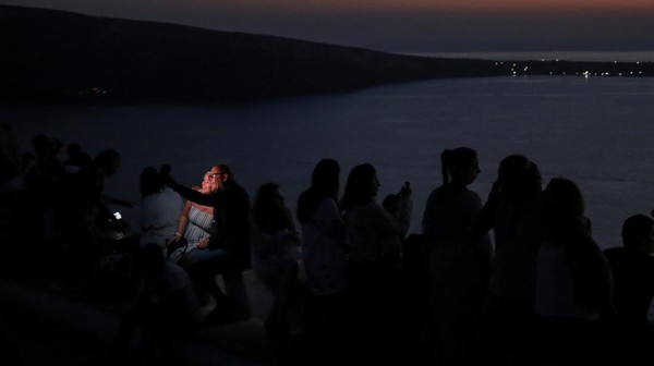 Wisatawan menyaksikan matahari terbenam dari kastil Oia, di pulau Santorini, Yunani, Selasa (30/8/2022) waktu setempat. Â Wisatawan menyaksikan matahari terbenam dari kastil Oia, di pulau Santorini, Yunani, Selasa (30/8/2022) waktu setempat. Â