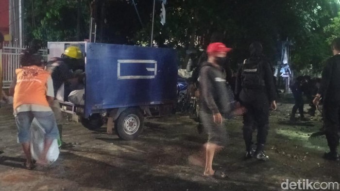 petugas kebersihan Sejumlah petugas kebersihan dibantu Brimob mulai membersihkan sampah dan material sisa demo sekitar pukul 23.30 Wita di Jalan AP Pettarani Makassar, Senin (5/9/2022).