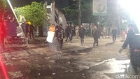 Foto: Petugas Brimob yang masih berjaga di depan UNM turut membantu petugas kebersihan. (Isak Pasabuan/detikSulsel)