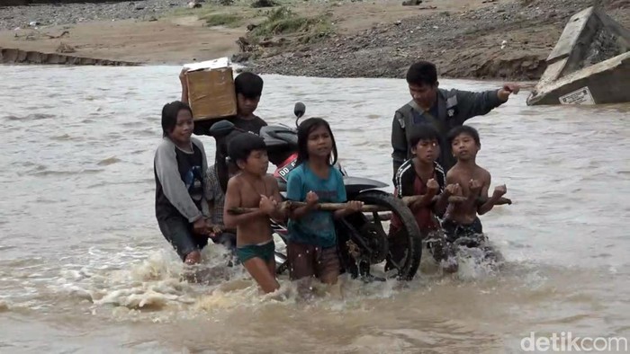 Anak-anak membantu warga menyeberangkan sepeda motor di Sungai Mambu di Kabupaten Polewali Mandar, Sulawesi Barat (Sulbar).