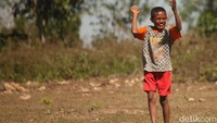 Bocah-bocah ini asyik bermain sepakbola di tanah lapang.  