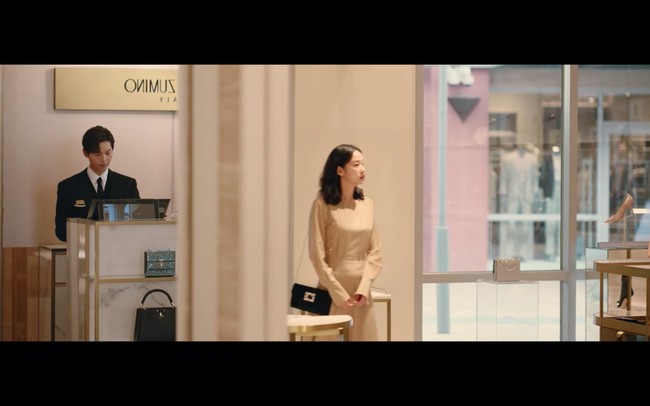 Kim Go Eun kemudian mendatangi toko sepatu mewah di mana dia bertemu dengan Song Joong Ki yang tampil sebagai cameo Little Women. Sang aktris memakai busana yang lebih mewah. Ada long sleeve dress koleksi Joseph seharga Rp 14 jutaan dan tas mewah Roger Vivier seharga Rp 25,2 jutaan. Foto: dok. Netflix