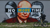 Pesepeda melintas di depan mural karya seniman Tuse Jaworski. Terdapat mural wajah Hitler, Putin dan Stalin dengan ditutup tulisan pada bagian mata No More Time.