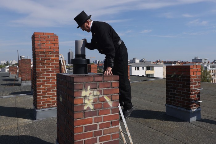 1421007284 BERLIN, GERMANY - SEPTEMBER 05: Chimney sweep Norbert Skrobek takes a photo of a chimney opening on the roof of an apartment building on September 05, 2022 in Berlin, Germany. Skrobek says he is facing enormous demand from Berliners seeking to use coal or wood to heat their apartments as an alternative to natural gas due to skyrocketing energy prices. Many older Berlin apartments have disused stoves that are still functional but require maintenance or certification to be restarted. Chimney sweeps in Germany adhere to a very traditional practice that includes their distinctive work clothes little changed from the 19th century. While actually cleaning soot and ash once dominated their labour, today they also perform inspections, consult clients on energy efficiency and determine parameters for installation of new heating systems. Energy prices have risen enormously in Germany and across Europe this year due to the consequences of Russia's ongoing war in Ukraine. (Photo by Sean Gallup/Getty Images)
