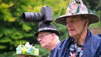 Seorang pria mengenakan topi kamera di Festival Topi Bridport. Festival topi ini menampilkan peserta dengan beragam hiasan unik hingga elegan.