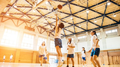 Japanese Junior High School girl friends playing basketball in the School GYM.