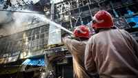 Para petugas pemadam berusaha memadamkan api yang menghanguskan sebuah bangunan di pasar tersebut. Lebih dari 30 unit mobil pemadam kebakaran dikerahkan ke lokasi untuk memadamkan api dan mencegah meluasnya api. (Sanchit Khanna/Getty Images)