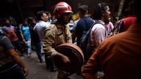 Petugas pemadam kebakaran mendatangi titik kebakaran yang ada di dalam pasar melewati pedagang-pedagang yang masih santai berkumpul di dalam pasar tersebut. (Salman Ali/Getty Images)