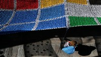 Seorang pejalan kaki melintas di bawah kanopi yang terbuat dari kantong plastik di Valverde de la Vera, Spanyol.