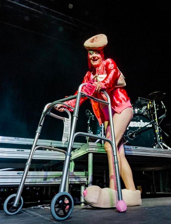 Peaches juga tampil nyeleneh menggunakan alat bantu jalan. Menggunakan jaket pink, dia melengkapi penampilannya dengan menggunakan topi berbentuk kelamin wanita dan sepatu berbentuk payudara. Foto: dok. Instagram/@peachesnisker