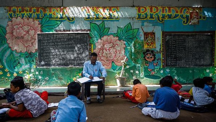 Semangat Guru di India Ajar Anak-anak di Kolong Jembatan NEW DELHI, INDIA - SEPTEMBER 05: Teacher Rajesh Kumar teaches Children at a makeshift school under a metro bridge on World Teachers' Day in New Delhi, India on September 05, 2022. The free school underneath the metro bridge is run by teacher Rajesh Kumar and Laxmi Chandra for children who come from the slums situated adjacent to the Yamuna river. (Photo by Amarjeet Kumar Singh/Anadolu Agency via Getty Images)