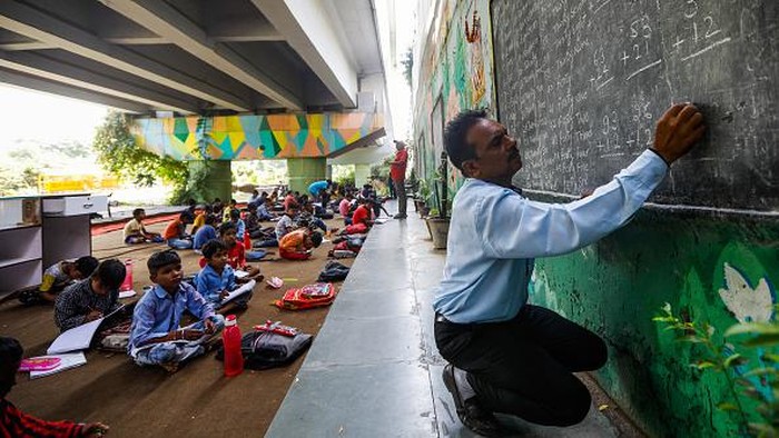 NEW DELHI, INDIA - SEPTEMBER 05: Teacher Rajesh Kumar teaches Children at a makeshift school under a metro bridge on World Teachers' Day in New Delhi, India on September 05, 2022. The free school underneath the metro bridge is run by teacher Rajesh Kumar and Laxmi Chandra for children who come from the slums situated adjacent to the Yamuna river. (Photo by Amarjeet Kumar Singh/Anadolu Agency via Getty Images)
