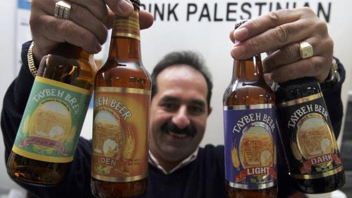 Seruput Taybeh, Bir Halal dari Palestina TOPSHOT - A bartender serves visitors on September 2, 2022, during the annual annual Oktoberfest beer festival in the village of Taybeh in the village of Taybeh, east of the occupied West Bank city of Ramallah, home of the Palestinian Taybeh brewery founded in 1994. - Ever since 2005, the Taybeh brewery has been brewing beer under challenging circumstances. Now the brewery is run by a woman, Madees Khoury, adding an extra layer of complication. Run as a two-day weekend event, Oktoberfest at Taybeh is as much about Palestinian identity as it is about drinking beer. (Photo by Abbas MOMANI / AFP) (Photo by ABBAS MOMANI/AFP via Getty Images)