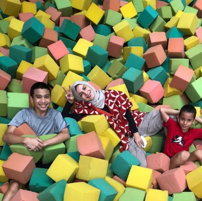 Tampil berhijab, Wanda terlihat sedang menikmati momen bersama buah hatinya di arena permainan bounce. Wanda Hamidah memakai hijab segi empat abu-abu, blouse model kimono merah dilengkapi manset hitam dan celana warna abu-abu. Foto: Dok. Instagram @wanda_hamidah.