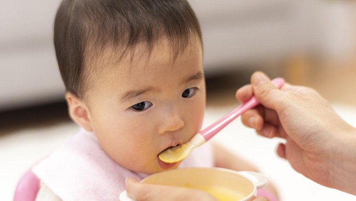 Mother feeds 0-year-old baby with baby food