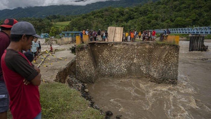 Jembatan di Sigi Sulteng Tergerus Banjir Bandang Warga menyaksikan jembatan yang putus akibat tergerus banjir di Desa Pakuli, Gumbasa, Sigi, Sulawesi Tengah, Selasa (6/9/2022). Jembatan yang berada di ruas jalan Trans Palu-Kulawi dan menghubungkan dengan sejumlah kecamatan di Kabupaten Sigi itu terputus karena terdampak banjir yang terjadi akibat jebolnya tanggul Sungai Gumbasa pada Selasa (6/9) dan saat ini warga harus menempuh jalan alternatif sejauh 60 kilometer untuk bisa sampai ke Kota Palu. ANTARA FOTO/Basri Marzuki/tom.