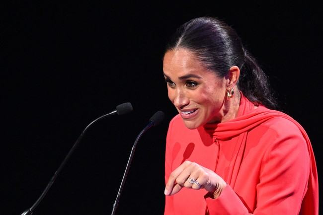 Rambut panjang Meghan Markle dikuncir sederhana dengan gaya ponytail. Sepasang anting emas pun terlihat menghasi telinganya. (Foto: AFP via Getty Images/OLI SCARFF)