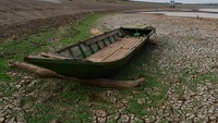 Bangkal kapal kayu terlihat di dasar waduk. Waduk Dawuhan yang memiliki daerah irigasi seluas 2.823 hektare sawah tersebut tinggal menyisakan sedikit air akibat musim kemarau.