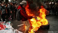 Massa membentuk lingkaran dan menyaksikan ban terbakar. 
