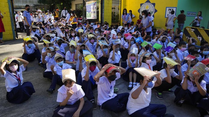 A student places her hands on her head for protection during an earthquake drill at an elementary school in Metro Manila, Philippines on Thursday Sept. 8, 2022. The Philippines conducted its third quarter nationwide earthquake drill as part of efforts to make the public aware of protocols and response during a disaster. (AP Photo/Aaron Favila)