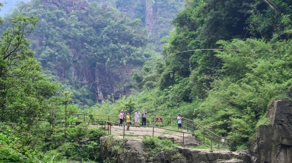Pengunjung melewati jembatan yang dikelilingi tebing. Taman ini terletak di kaki Pegunungan Nanling dan bagian utara Provinsi Guangdong, Ruyang.
