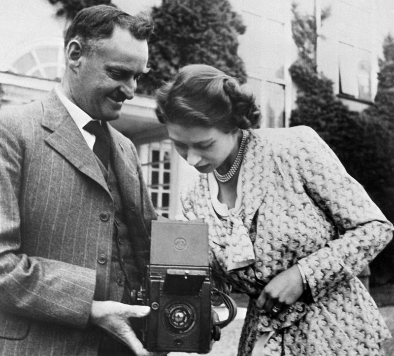 British Royal Queen Elizabeth II, wearing a headscarf and a waxed jacket, takes a picture with her Leica M6 camera at the Royal Windsor Horse Show, held at Windsor Home Park in Windsor, Berkshire, England, 12th May 1989. (Photo by Tim Graham Photo Library via Getty Images)