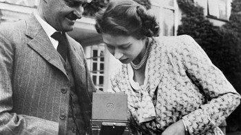 Ratu ELizabeth II melihat hasil jepretan seorang fotografer pada Juli 1949. Ratu Inggrius tersebut dikenal menyukai dunia fotografi sejak kecil. (AFP via Getty Images)