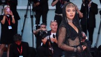 Gaun jaring-jaring panjang itu dipadu sepatu hak tinggi hitam dan aksesori kalung bernuansa emas. (Foto: Getty Images/Maria Moratti)