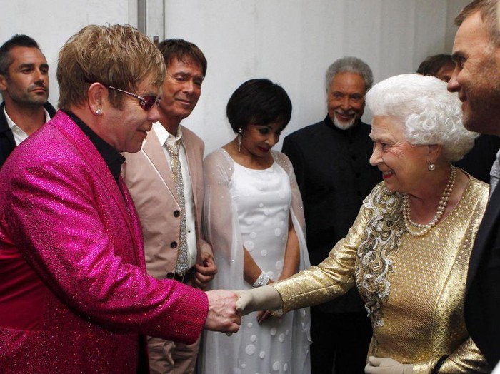 Queen Elizabeth II meets Sir Elton John backstage as British singer Robbie Williams (R) watches during the Diamond Jubilee Concert outside Buckingham Palace in London, on June 4, 20112. A chain of more than 4,200 beacons began to flare across the globe Monday to mark Queen Elizabeth IIs diamond jubilee, with the last to be lit by the monarch at a star-studded concert at Buckingham Palace. AFP PHOTO / Dave Thompson /POOL (Photo by Dave Thompson / POOL / AFP) (Photo by DAVE THOMPSON/POOL/AFP via Getty Images)
