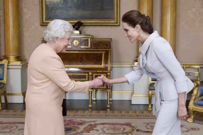 LONDON, ENGLAND - OCTOBER 10:  Actress Angelina Jolie is presented with the Insignia of an Honorary Dame Grand Cross of the Most Distinguished Order of St Michael and St George by Queen Elizabeth II in the 1844 Room on October 10, 2014 at Buckingham Palace, London. Jolie is receiving an honorary damehood (DCMG) for services to UK foreign policy and the campaign to end war zone sexual violence.  (Photo by Anthony Devlin - WPA Pool/Getty Images)