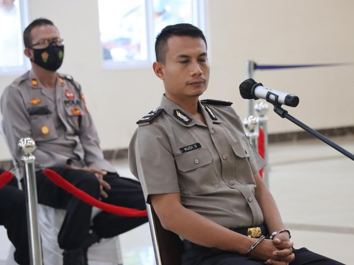 Aipda Rudy menjalani sidang kode etik karena menembak rekannya Aipda Ahmad Karnain hingga tewas. Saat proses persidangan tangan Rudy diborgol.