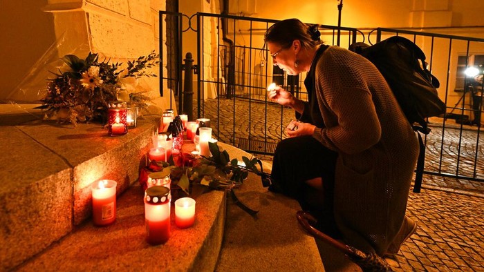 A woman lights a candle in front of the British Embassy to express grief over Queen Elizabeth's death, in Prague, Czech Republic, Thursday, Sept. 8, 2022. (Rihova Michaela/CTK via AP)