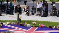 Seorang pelayat meninggalkan bunga saat awak media berkumpul di luar Kedutaan Besar Inggris di Washington, Amerika Serikat, Kamis (8/9/2022) waktu setempat. (AP Photo/Patrick Semansky)
