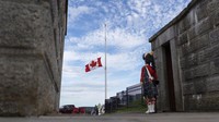 Bendera Kanada berkibar setengah tiang saat penjaga dalam pakaian tradisional berdiri di Benteng Halifax di Halifax, Nova Scotia, Kanada, Kamis (8/9/2022) waktu setempat. (AP Photo/Darren Calabrese)  
