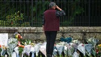 Seorang warga memberikan hormat atas kepergian Ratu Elizabeth di depan Istana Buckingham. (Jeff J Mitchell/Getty Images)
