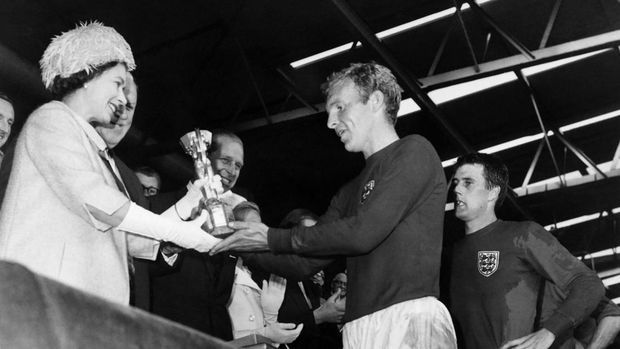Britain's Queen Elizabeth of England presents the Jules Rimet Cup to Bobby Moore, captain of England's national soccer team, as her husband Prince Philip (C) and forward Geoff Hurst (R) look on after England beat West Germany 4-2 in extra time in the World Cup final 30 July 1966 at Wembley stadium in London. - Hurst scored three goals, two of them in extra time, to help England win its first World title. (Photo by - / AFP) (Photo by -/AFP via Getty Images)