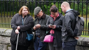 Warga berada di depan istana Balmoral di mana Ratu Elizabeth meninggal dunia, dengan mengakses berita online. Foto: Getty Images
