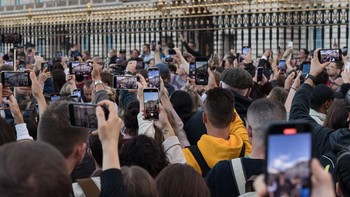Warga ramai-ramai merekam dengan ponsel di luar Buckingham Palace sesaat setelah pengumuman wafatnya Ratu Elizabeth II dan bendera Inggris diturunkan setengah tiang. Foto: Getty Images