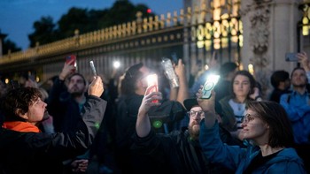 Warga menyalakan lampu di ponselnya sebagai tanda penghormatan. Foto: Getty Images