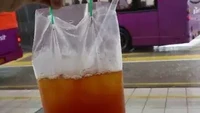 Perhatian dengan pelanggannya, penjual es teh manis ini punya cara agar pelanggan tak kedinginan. Bagian atas plastik diberi dua lubang dan plastik untuk menentengnya. Foto: 1cak.com