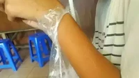 Tak mau ribet, seorang pria punya cara jitu memegang es teh manis tanpa kedinginan. Bagian atas plastiknya dilubangi dan disangkutkan pada pergelangan tangannya. Foto: 1cak.com