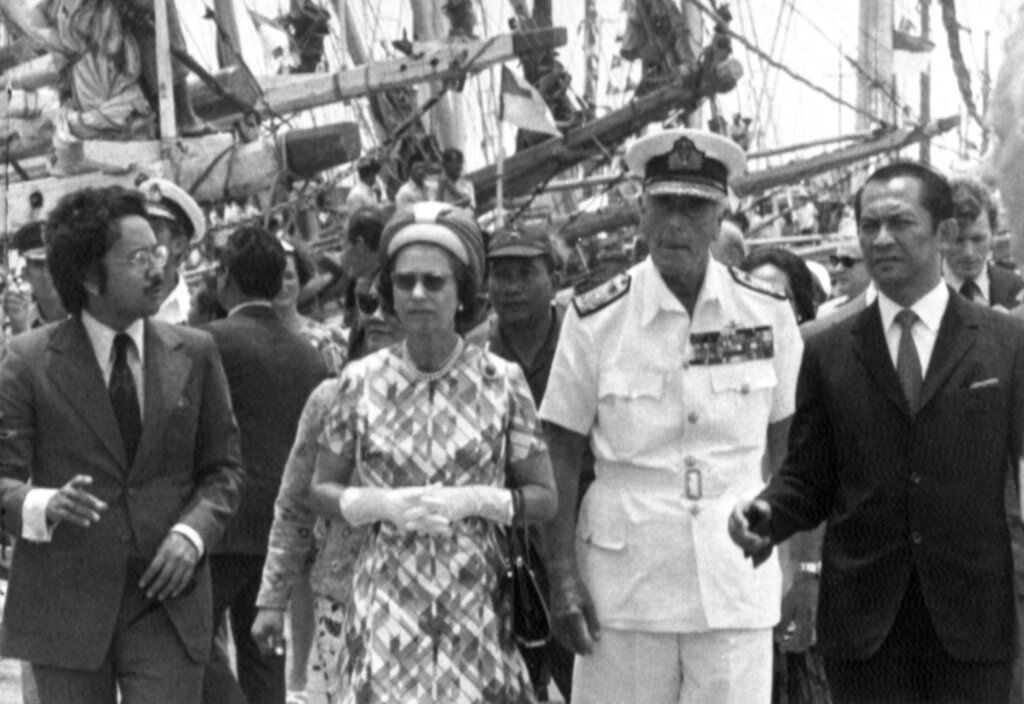 Britain's Queen Elizabeth II and Earl Mountbatten, in white naval uniform, accompanied by Jakarta Governor Ali Sadikin, right, stroll along the pier at Sunda Kelapa, on March 19, 1974, to view the schooners berthed there. (AP Photo)