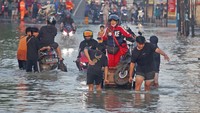 Pengendara motor menggunakan jasa ojek gerbok untuk melintasi banjir