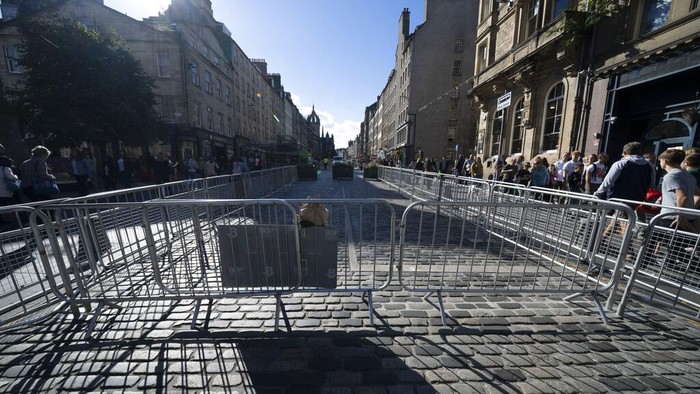 Polisi dan Warga Menanti Iringan Jenazah Ratu Elizabeth II Police and security guards are seen on the Royal Mile as Edinburgh prepares for thousands of well-wishers to line streets of the city when the Queen's coffin is brought to the Palace of Holyroodhouse, Edinburgh, Scotland, Saturday, Sept. 10, 2022. Queen Elizabeth II, Britain's longest-reigning monarch and a rock of stability across much of a turbulent century, died Thursday Sept. 8, 2022, after 70 years on the throne. She was 96. (AP Photo/Jon Super)