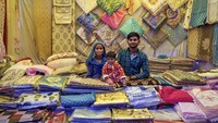 Sepasang suami istri Rekha Devi Vijay Kumar dan putranya Amit yang berusia 1 tahun, menjual seprai dan bantal di pameran lokal di Dharmsala, India, Rabu (7/9/2022).