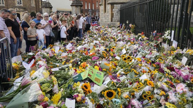 Banyak warga meninggalkan bunga, terutama bunga matahari, di luar Kastil Windsor untuk menghormati mendiang Ratu Elizabeth II Crowds of people walk to Windsor Castle to bring flowers, in Windsor, England, Sunday, Sept. 11, 2022. Queen Elizabeth II, Britains longest-reigning monarch died Thursday Sept. 8, 2022, after 70 years on the throne. (AP Photo/Martin Meissner)