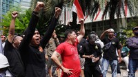 Mereka tetap berunjuk rasa meski sempat diguyur hujan.